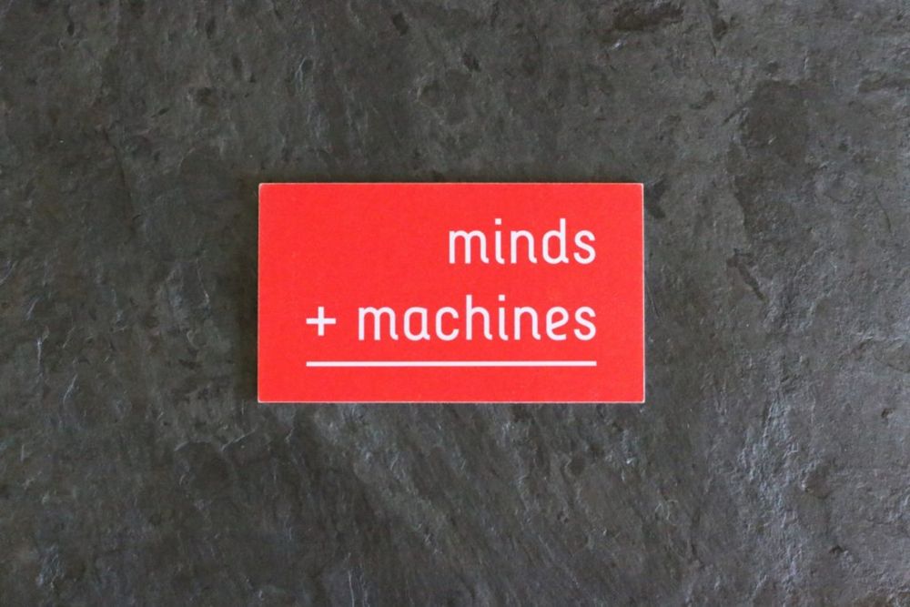 Minds + Machines red business card on slate